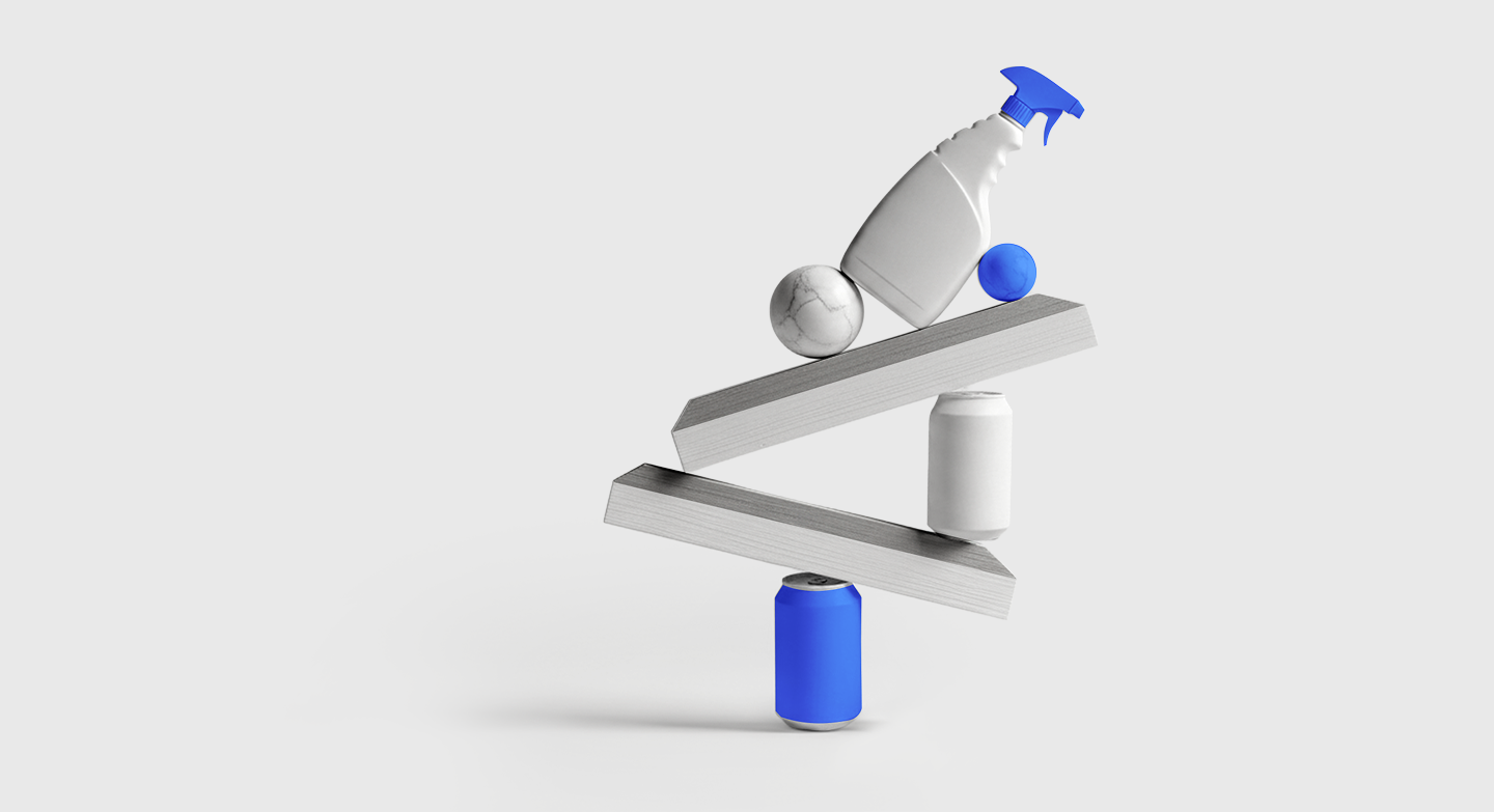 Abstract 3D balancing sculpture of grey and blue geometric objects stacked on angled platforms against a light grey background.